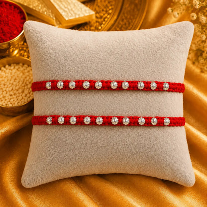 Red Rakhi with silver beads displayed on a beige cushion with golden festive background
