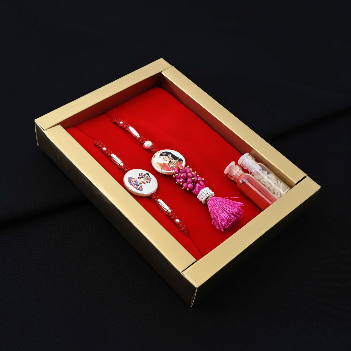 Elegant Rakhi with a silver Raja Rani motif, pink theme, kumkum, and rice, ideal for boys.