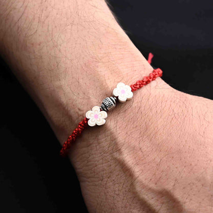 Elegant Rakhi with silver beads and two cream flowers, ideal for boys.