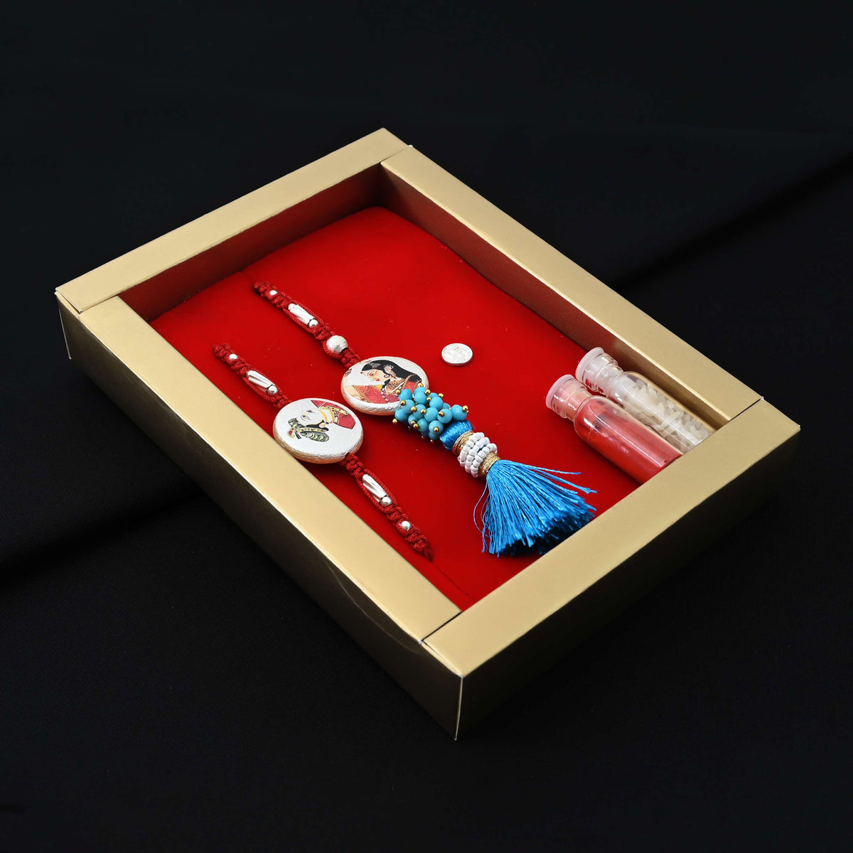 Elegant Rakhi with silver Raja Rani motif, blue theme, kumkum, and rice, ideal for boys.