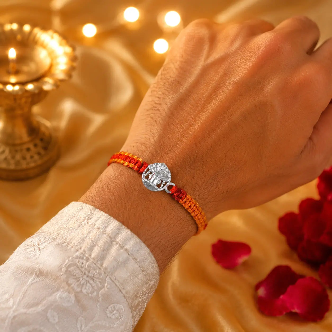 925 Sterling Silver Shivling Rakhi with traditional red and orange braided thread for Raksha Bandhan displayed on a premium beige velvet cushion.