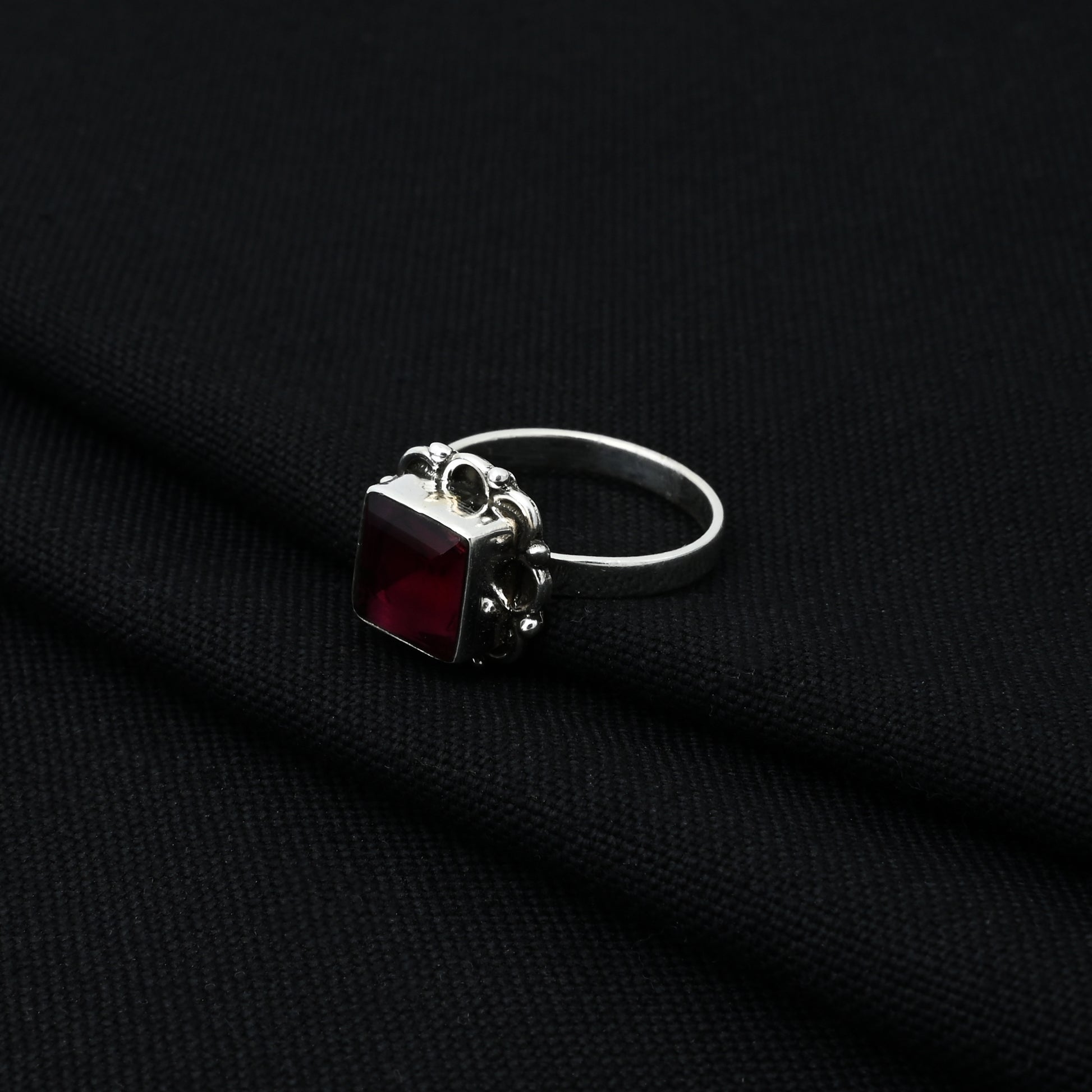 Stylish silver ring with a deep maroon gem, perfect for adding a touch of elegance and color to any outfit.