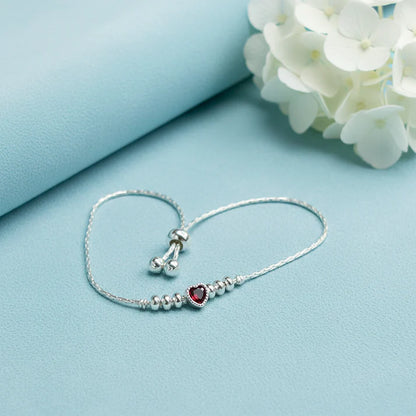 925 sterling silver adjustable bracelet with a purple heart-shaped gemstone, silver beads, and sliding clasp displayed on a light Red velvet jewelry box.