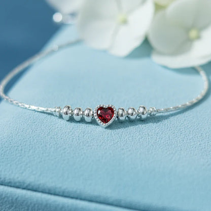 925 sterling silver adjustable bracelet with a purple heart-shaped gemstone, silver beads, and sliding clasp displayed on a light Red velvet jewelry box.