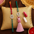 Bhai Bhabhi Rakhi set with silver stone circular charm, red green thread and pink tassel Lumba Rakhi on beige velvet cushion festive background
