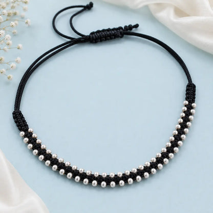 Black thread anklet with silver beads worn on a woman's anklet