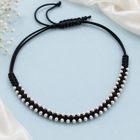 Black thread anklet with silver beads worn on a woman's anklet