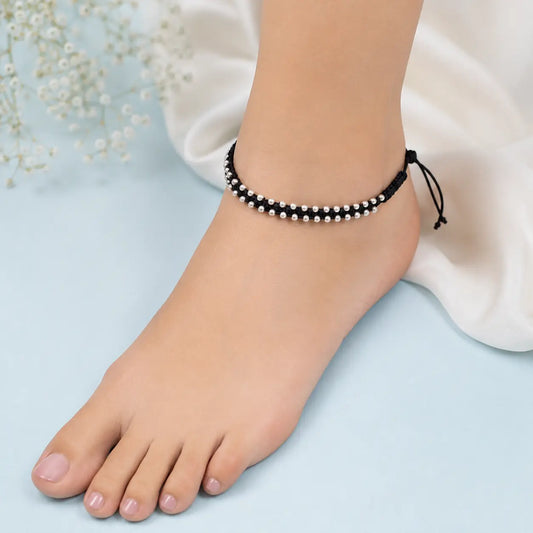 Black thread anklet with silver beads worn on a woman's anklet