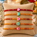Colorful kids Rakhi set of 5 with cartoon panda, watermelon, flower and paw design displayed on beige cushion with festive diya background