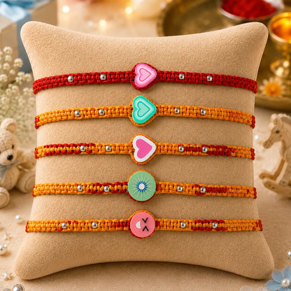 Colorful kids Rakhi set of 5 with cartoon panda, watermelon, flower and paw design displayed on beige cushion with festive diya background
