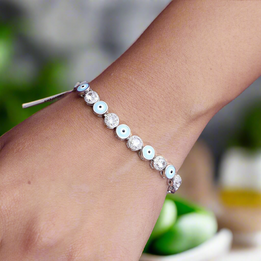 Silver chain bracelet with an evil eye charm and a sparkling white gemstone for protection.