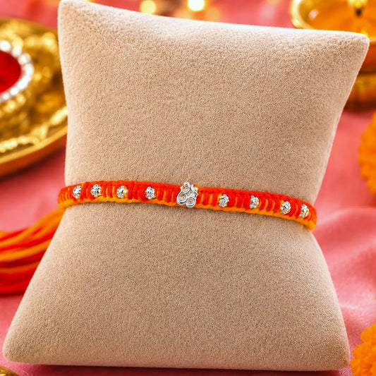 Set of One orange and yellow thread designer silver rakhis displayed on a beige cushion