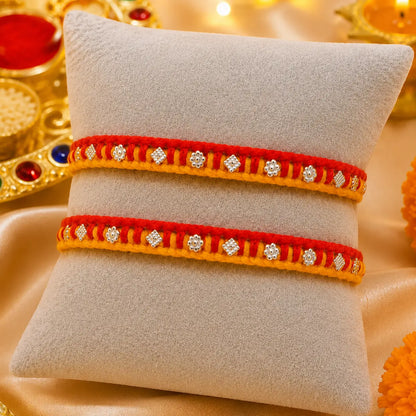 Traditional red and yellow Rakhi with silver detailing displayed on a cream velvet cushion