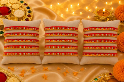 Traditional red and yellow Rakhi with silver detailing displayed on a cream velvet cushion