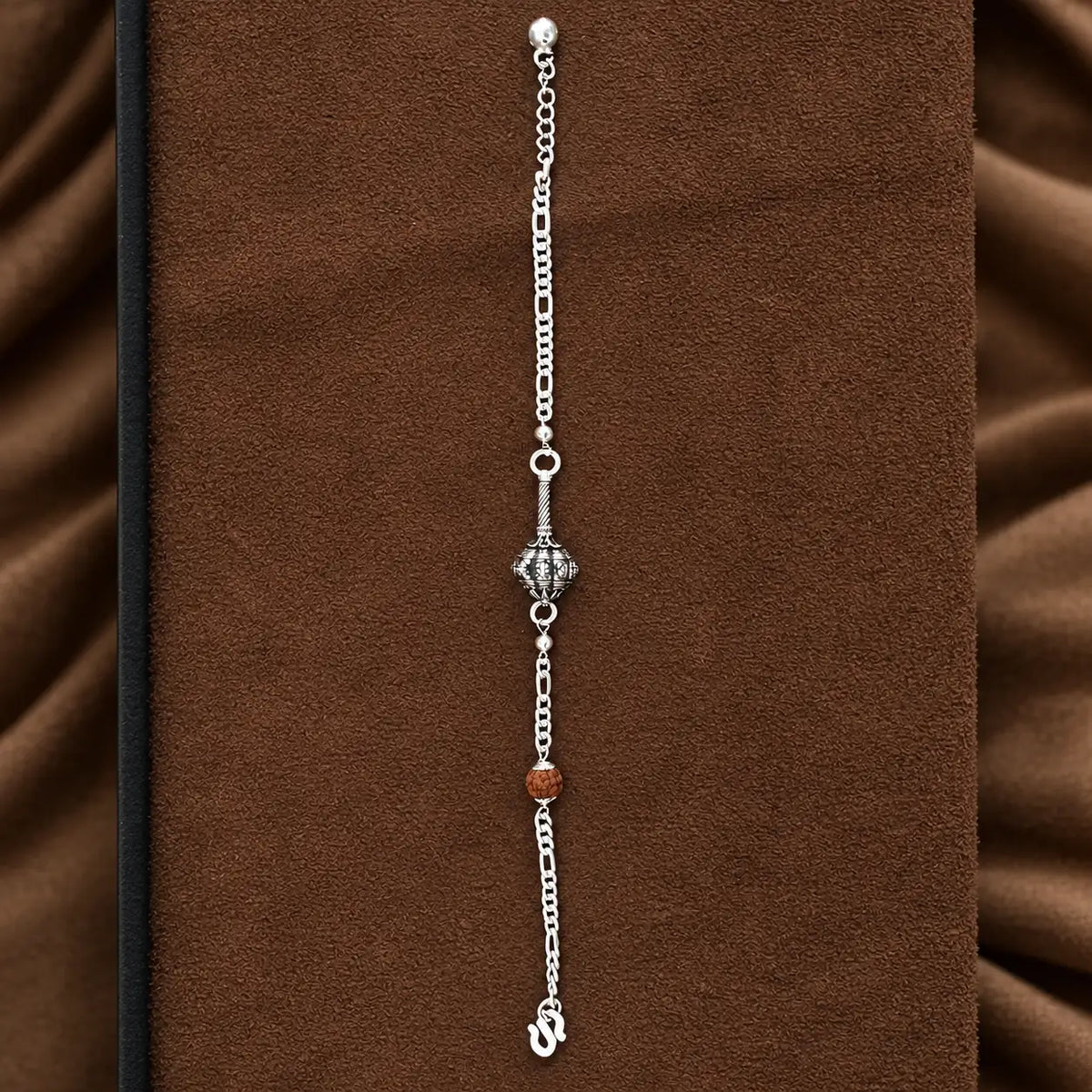 Hanuman Ji Ki Ghota silver bracelet with decorative silver chain and brown Rudraksha-style bead on a brown jewellery display