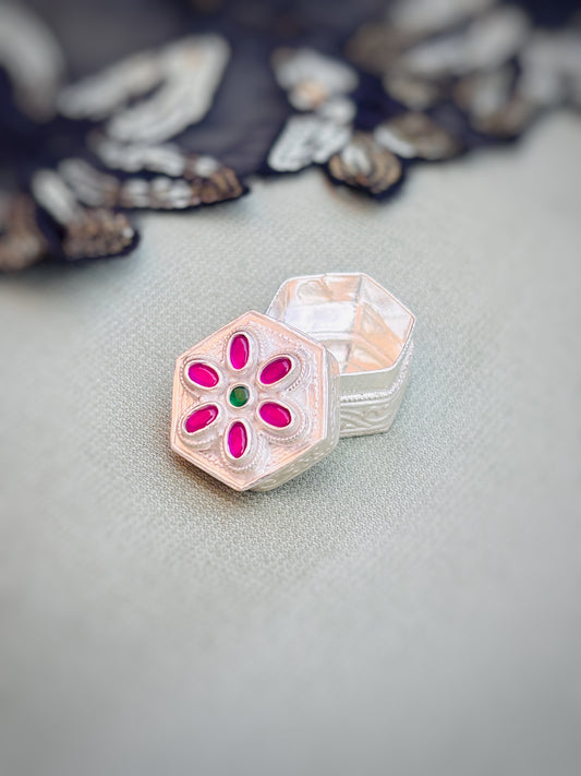 Elegant silver sindor box featuring pink stones and a green center stone in a flower design.