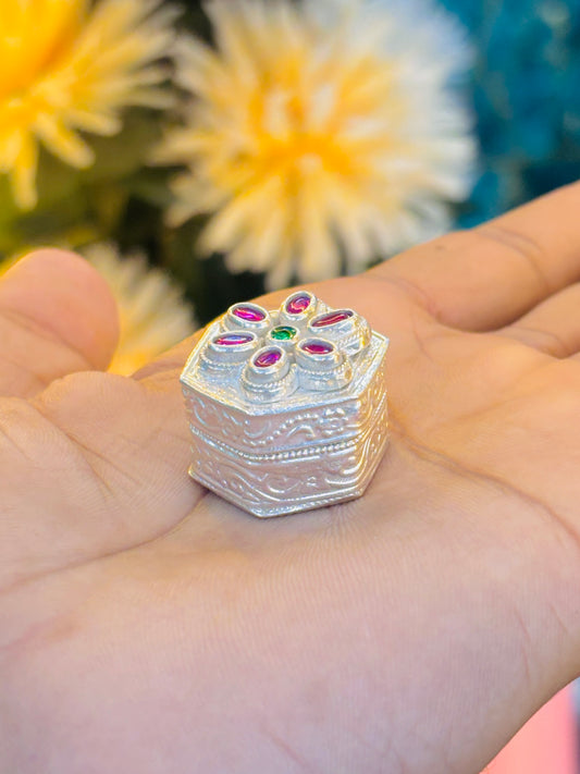 Handcrafted silver sindor box with pink stones and green center stone in flower motif.