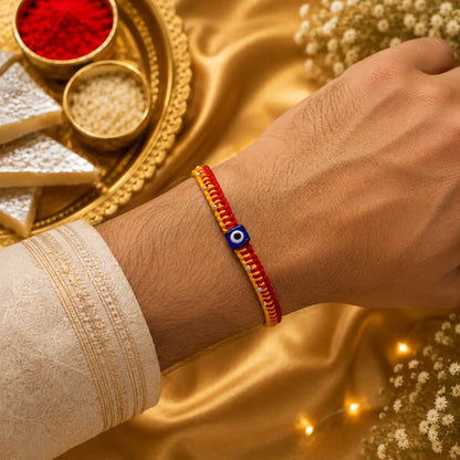 Premium handmade Evil Eye Rakhi with blue protective bead on a cream cushion, luxury golden festive background with kumkum, rice, sweets, and flowers for Raksha Bandhan.