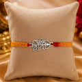 Shiv silver rakhi with Hindi Shiv symbol and Trishul design on red yellow thread placed on velvet cushion