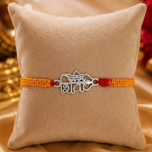 Shiv silver rakhi with Hindi Shiv symbol and Trishul design on red yellow thread placed on velvet cushion