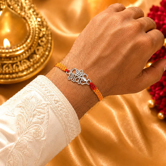 Shiv silver rakhi with Hindi Shiv symbol and Trishul design on red yellow thread placed on velvet cushion