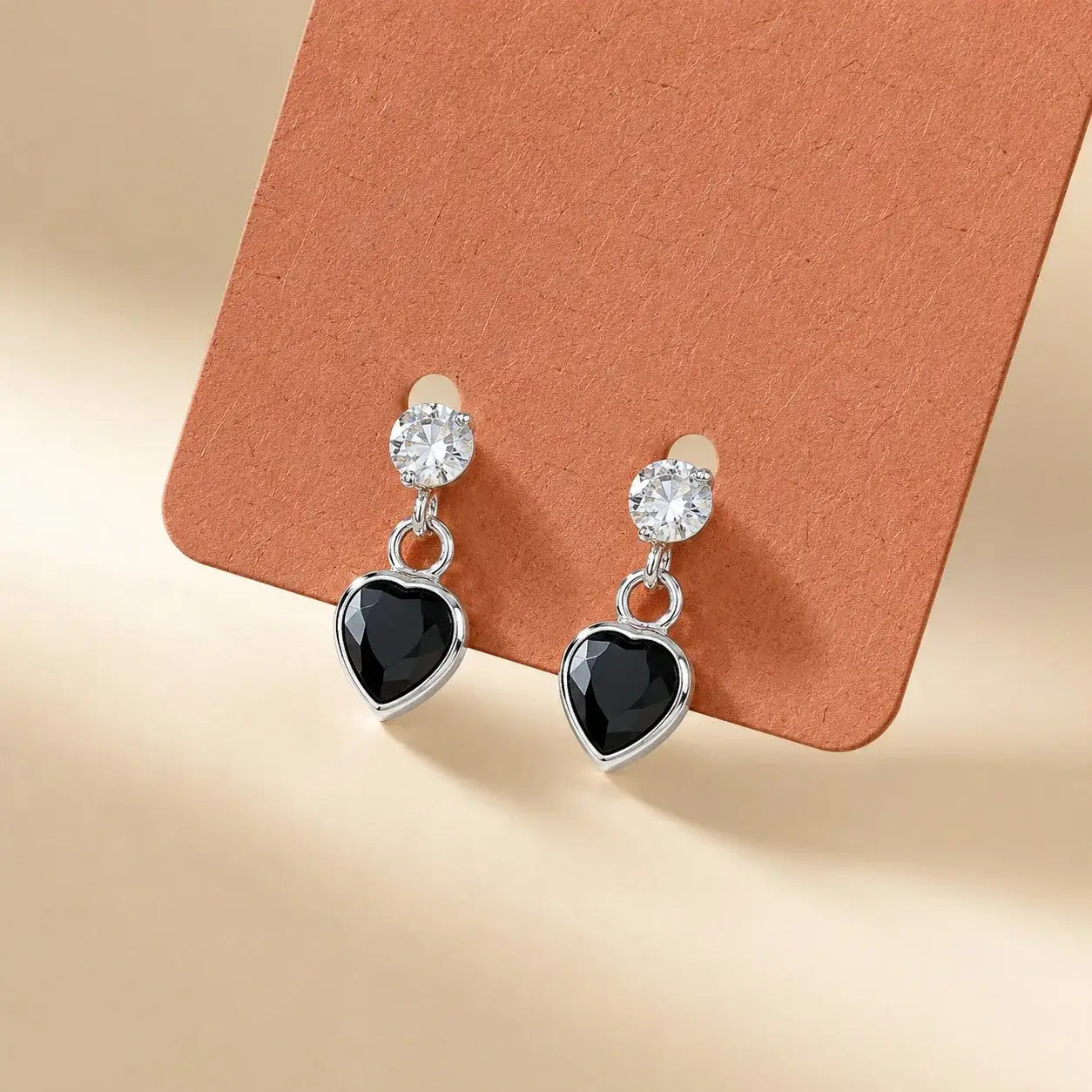 Silver black heart drop stud earrings with sparkling Cubic Zirconia stones and polished silver-tone finish for women displayed on a jewelry card.