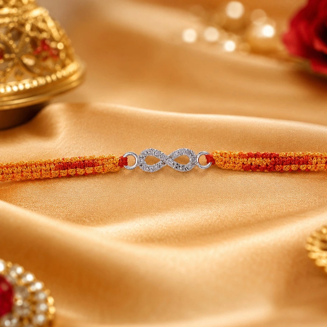 Silver Infinity BRO Rakhi for brother with sparkling infinity charm and orange-red handcrafted thread displayed on a beige velvet cushion
