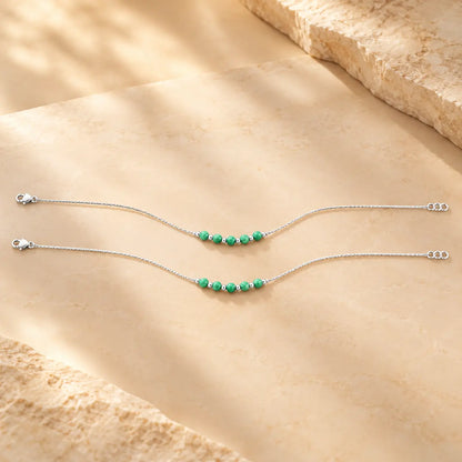 Silver anklet with green beads worn on a woman's ankle by Khushbu Jewellers