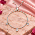 Silver beaded charm bracelet for women with adjustable slider clasp and dangling ball charms on a beige background