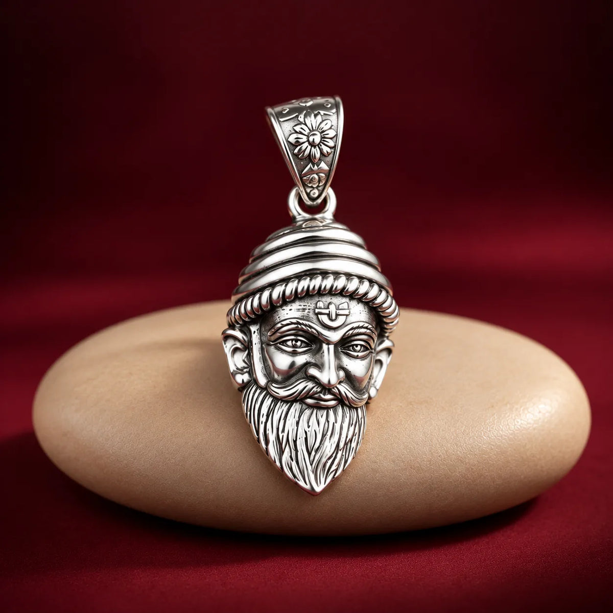 Silver Chhatrapati Shivaji Maharaj face pendant with detailed royal headgear, moustache, and beard on a white and dusty pink background