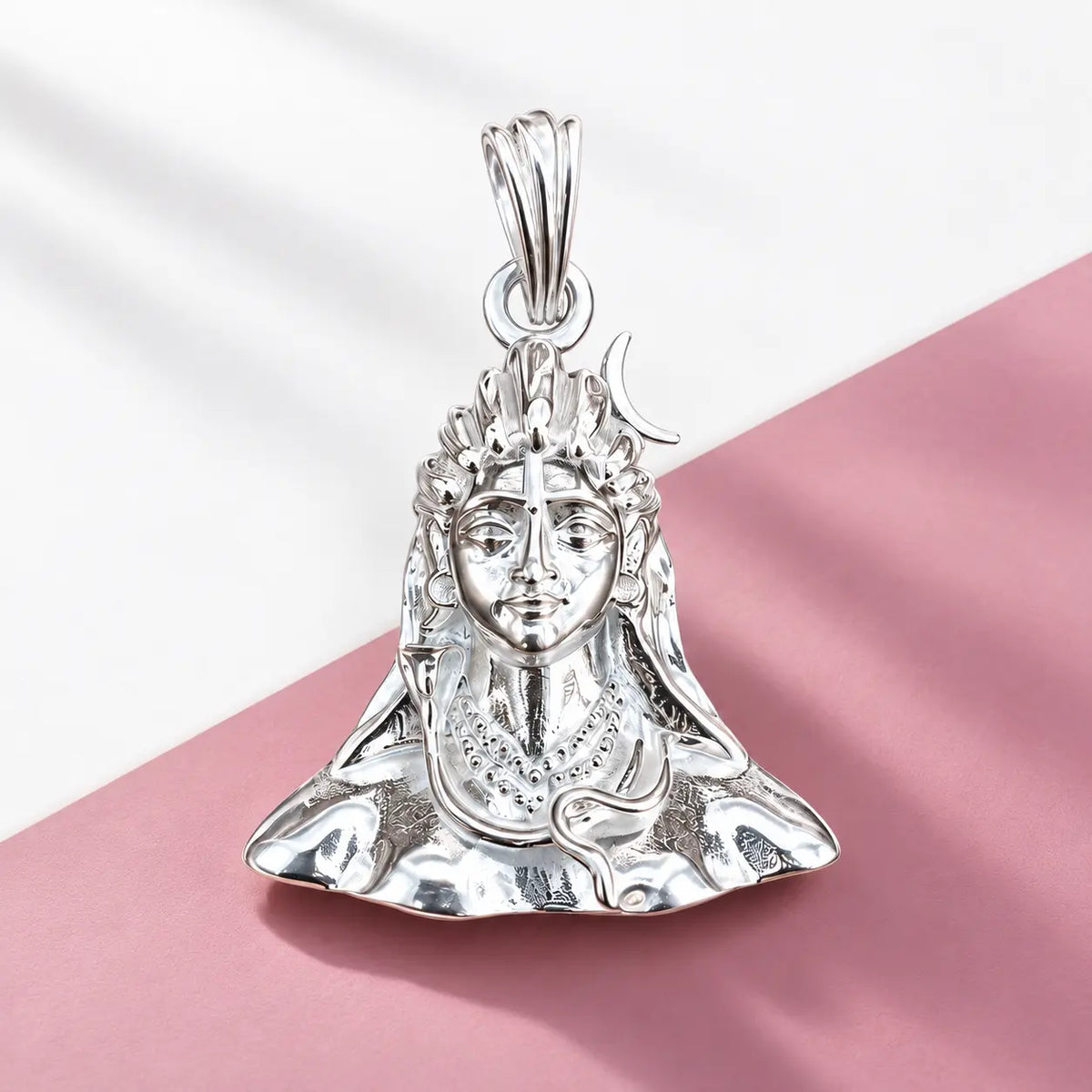 Silver Lord Shiva face pendant with crescent moon and detailed polished silver design on a warm beige background