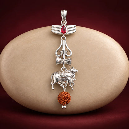 Silver Nandi Mahadev Trishul pendant with red gemstone and Rudraksha bead on a pale sage green background