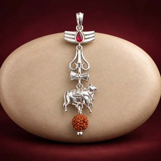 Silver Nandi Mahadev Trishul pendant with red gemstone and Rudraksha bead on a pale sage green background
