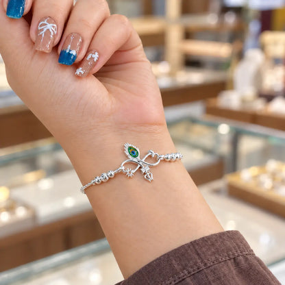 Silver bracelet with colorful peacock feather eye, Trishul and sun charms worn on a woman's wrist