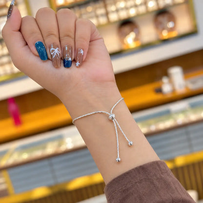 Silver bracelet with colorful peacock feather eye, Trishul and sun charms worn on a woman's wrist