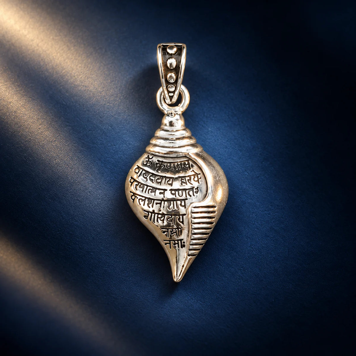 Silver Shankh pendant with engraved Sanskrit mantra and polished shell-shaped design on a pale sage green background