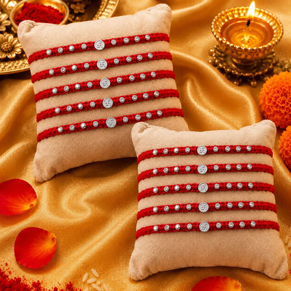 Silver Swastik Rakhi with red braided thread and silver beads on a festive cream cushion