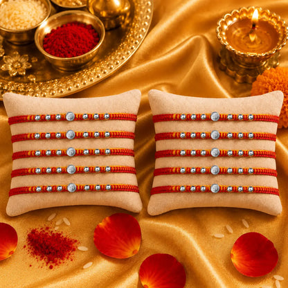 Premium silver Swastik Rakhi with red and yellow thread and silver beads on a beige cushion