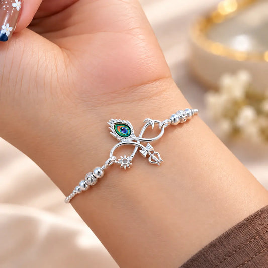 Silver bracelet with colorful peacock feather eye, Trishul and sun charms worn on a woman's wrist