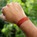 Traditional red and yellow Moli Kalava sacred thread tied on a man's wrist