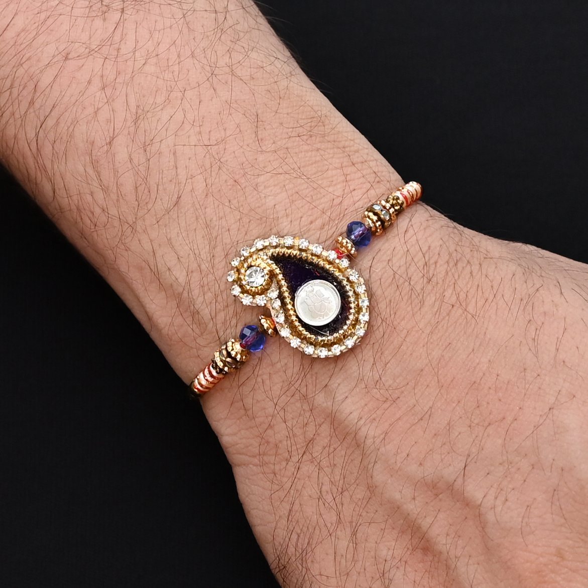 Elegant Ganesh Ji Rakhi with a black background and multiple colorful beads, ideal for boys