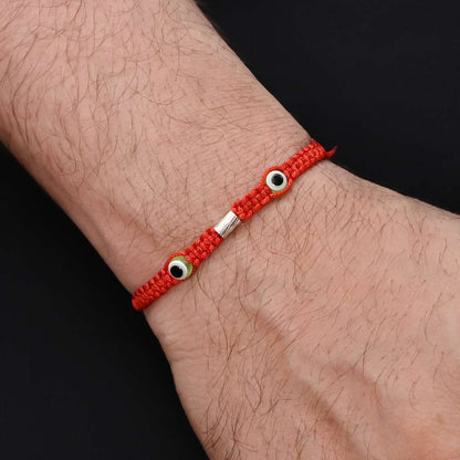 Elegant Rakhi with two green evil eyes in silver, ideal for boys.