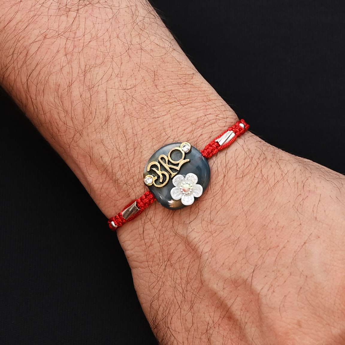 Elegant Rakhi with 'Bro' written in silver, set on a blue background and adorned with a white flower, ideal for boys.