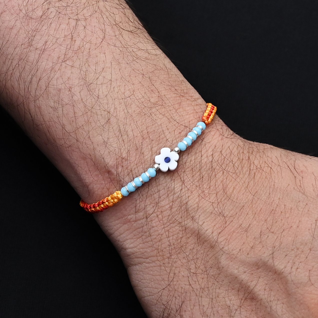 Elegant light blue flower design with silver and light blue beads, ideal Rakhi for boys.