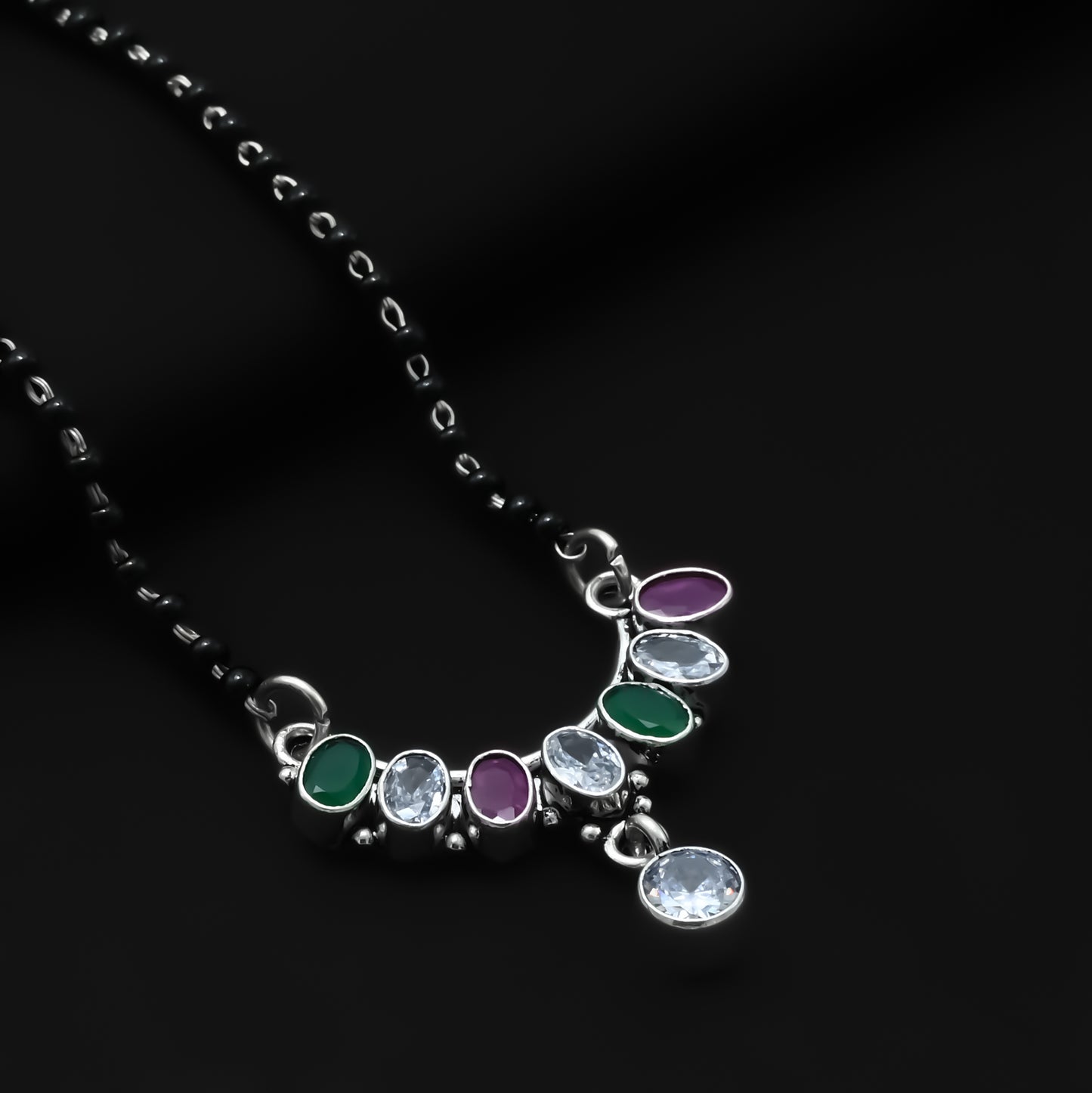 Charming sterling silver mangalsutra with a bow-shaped pendant and vibrant purple and green gemstones