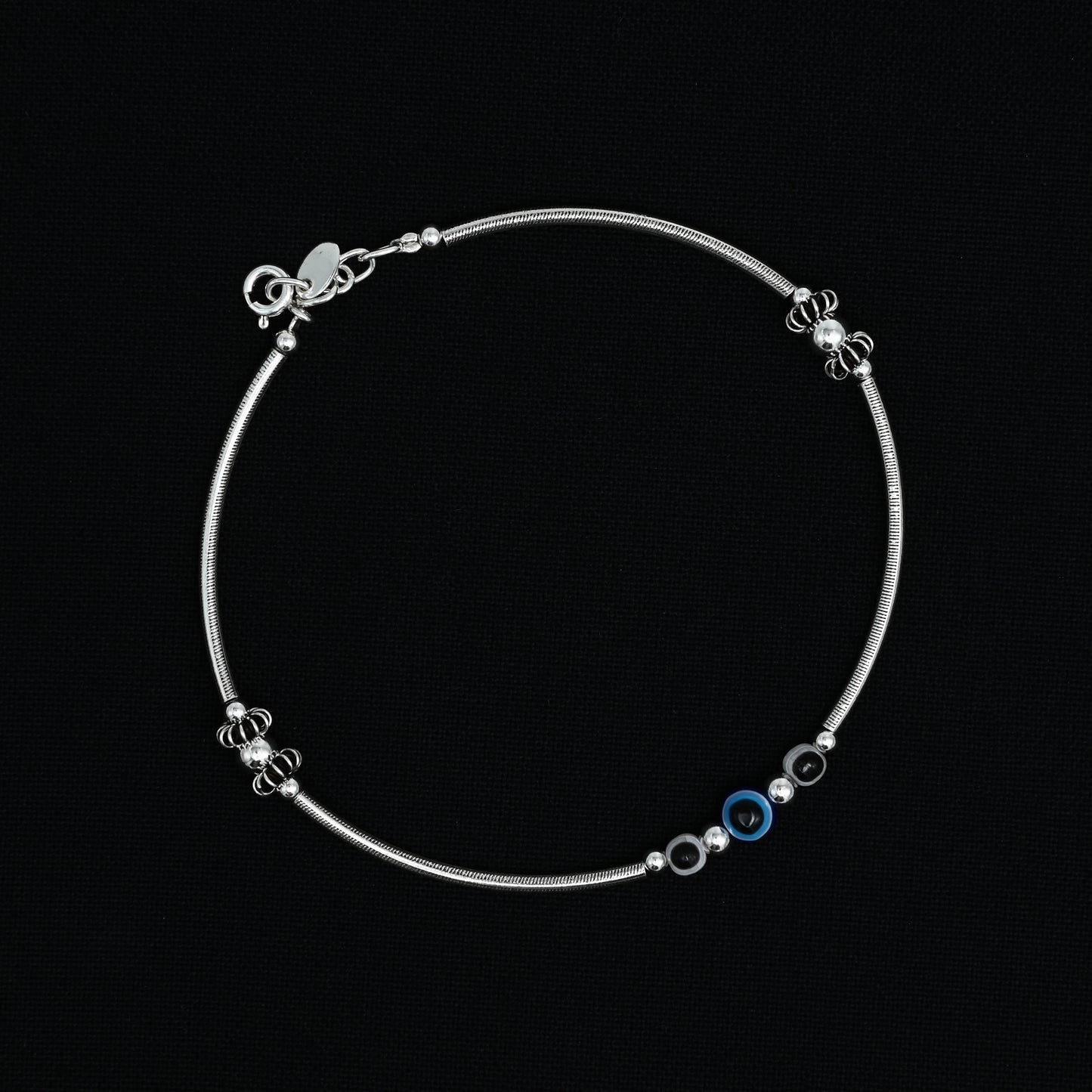 Charming silver anklet with a blue and black evil eye centerpiece, ideal for a trendy and symbolic addition to your look