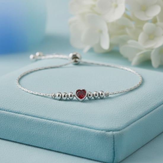 925 sterling silver adjustable bracelet with a purple heart-shaped gemstone, silver beads, and sliding clasp displayed on a light Red velvet jewelry box.