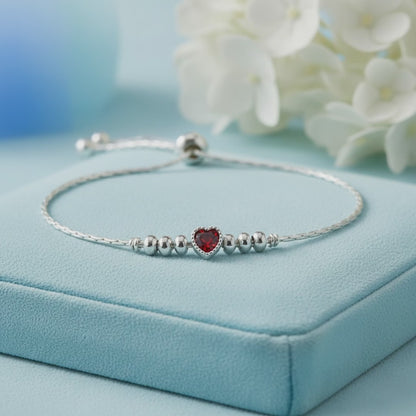 925 sterling silver adjustable bracelet with a purple heart-shaped gemstone, silver beads, and sliding clasp displayed on a light Red velvet jewelry box.